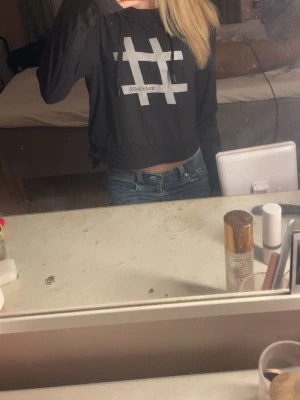 Svart croppad långärmad topp MXIM - Säljer en svart croppad långärmad topp från MXIM med stort vitt hashtag-tryck framtill. Tröjan har en avslappnad passform och är perfekt till jeans eller kjol. Snygg och enkel design som sticker ut med sitt grafiska tryck.