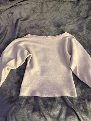 Ljusbeige stickad tröja med båtringning - En stilren ljusbeige stickad tröja med båtringad hals och långa ärmar. Tröjan har en rak passform och är tillverkad i ett mjukt, tunt stickat material som känns skönt mot huden. Perfekt för lager på lager och enkel att matcha med olika outfits.