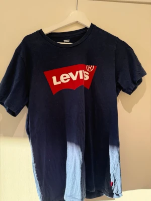 Marinblå Levi's t-shirt med logga - Snygg marinblå t-shirt från Levi's med den klassiska röda loggan tryckt på bröstet. T-shirten har rund halsringning och korta ärmar. Tillverkad i mjuk bomull som är skön att bära hela dagen.