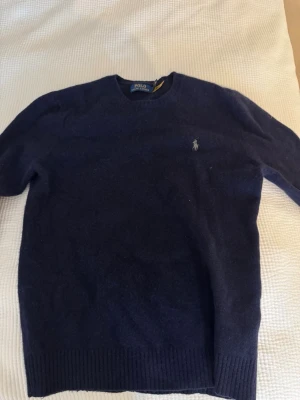 POLO RALPH LAUREN - Cashmere Hunternavy Crewneck - Mörkblå stickad tröja från Polo Ralph Lauren med rund halsringning och klassisk broderad logga på bröstet. Nypris 2695, säljes då den ej passar längre. Mycket gott skick, inget synligt slitage eller dylikt. 