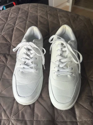 Vita Champion sneakers låga - Snygga helvita sneakers från Champion med klassisk låg siluett. Skorna har ovandel i syntetmaterial och mesh för extra andningsförmåga, samt vita snören och diskret Champion-logga broderad på hälen. Perfekta för en clean och stilren look.
