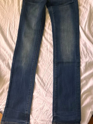 Blå raka jeans från G-Star RAW - Snygga blå jeans från G-Star RAW med raka ben och klassisk femficksmodell. Jeansen har en lätt tvättad look och är gjorda i denim med synliga kontrastsömmar. Perfekta för en avslappnad och stilren outfit.