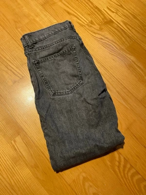 Grå raka jeans i klassisk modell - Säljer ett par grå jeans med rak passform och hög midja. Jeansen har fem fickor och stängs med knapp och dragkedja. Materialet är kraftig denim i bomull. Perfekta till en avslappnad och trendig stil. Storlek W32, L30. Säljer för 100kr.