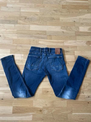 Blå slim fit jeans från Replay - Säljer ett par blå slim fit jeans från Replay med snygga slitningar och kontrastsömmar. Perfekta för dig som gillar en modern och avslappnad stil. Storlek: W30 L32. Dessa snygga jeans är knappt använda så dom är i riktigt bra skick🔥Skriv om du har några funderingar så löser vi ett bra pris!🤝✅