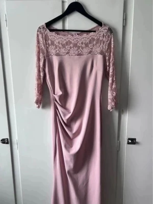 Ljusrosa långklänning med spetsärmar - Elegant ljusrosa långklänning med trekvarts spetsärmar och draperad detalj framtill. 