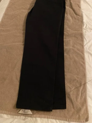 Svarta kostymbyxor från Dressman. Storlek 38W och 30L. - Snygga svarta kostymbyxor från Dressman  med rak passform och klassisk look. Byxorna har diskreta fickor och är perfekta för en stilren outfit. Materialet ser ut att vara mjukt och följsamt, vilket ger en bekväm känsla hela dagen.