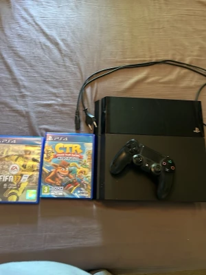 PlayStation 4 med handkontroll och spel - Säljer en svart PlayStation 4 med en matchande svart DualShock 4-handkontroll. Medföljer gör strömkabel samt två PS4-spel: FIFA 17 och Crash Team Racing Nitro-Fueled. Perfekt för dig som vill ha en komplett spelupplevelse direkt!