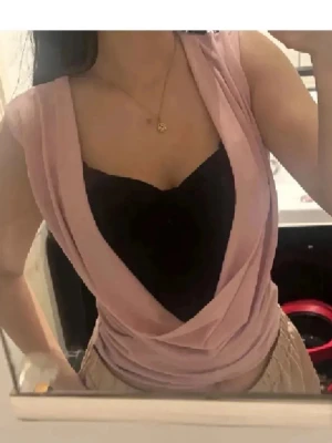 Sommartopp❤️ - Snygg rosa omlottopp med djup v-ringning och ärmlös design. Toppen har en draperad framsida och bärs här med ett svart linne under. Perfekt för dig som gillar trendiga och feminina plagg. Svarta under sitter fast😊