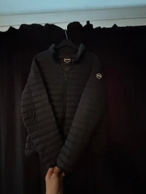 Svart dunjacka från Colmar - Snygg svart dunjacka från Colmar med diskret logga på ärmen. Jackan har quiltad design, dragkedja framtill och hög krage. Perfekt för kalla vinterdagar och riktigt lätt att bära. Klassisk och stilren modell som passar till det mesta. Skriv vid minsta fundering. Pris är inte hugget i sten!
