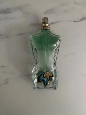 Jean Paul Gaultier Le Male parfym - Unik parfymflaska från Jean Paul Gaultier formad som en manlig torso i transparent grönt glas med en broderad detalj framtill. Flaskan har en metallisk spraytopp och är riktigt snygg att ha framme i badrummet.