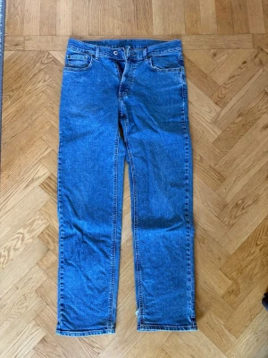 Blå raka jeans - Klassiska blå jeans med rak passform och fem fickor. Jeansen har normal midja, knappgylf och är tillverkade i slitstark denim. Perfekta för en avslappnad och tidlös stil.