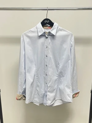 Skjorta - Vit skjorta från Burberry. Otroligt fint skick, inga större tecken på användning. De ikoniska mönstret i ärmar och krage. Storlek L sitter som en M.