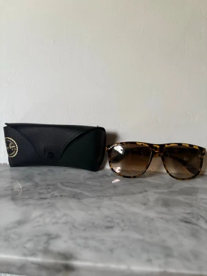 Ray-Ban leopardmönstrade solglasögon - Snygga solglasögon från Ray-Ban med leopardmönstrad båge och bruna tonade glas. Klassisk modell som ger en cool vibe. Kommer med original svart fodral med Ray-Ban-logga. Perfekt accessoar för soliga dagar. Har inte använt dem mycket tröttnade på dem rätt fort då jag säljer de nu, pris kan diskuteras vid snabb affär, ställ gärna frågor!