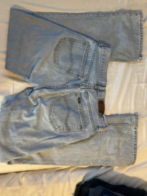 Ljusblå Denver jeans från Lee - Säljer ett par klassiska ljusblå Denver jeans från Lee i 100% bomull. Jeansen har en rak passform, fem fickor och tydliga sömmar. Perfekta för dig som gillar vintage vibe och tidlös denimstil.
