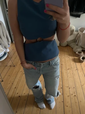 Blå snygg topp - Säljer en blå croppad topp med unik ringdetalj i midjan. Toppen är ärmlös och har en clean, modern look som passar perfekt till jeans eller kjol. Materialet känns mjukt och stretchigt, vilket gör den bekväm att bära hela dagen. Använd endast 1 gång❣️