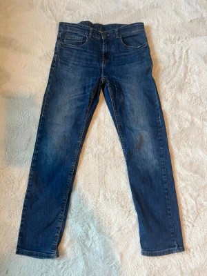 Mörkblå skinny jeans - Säljer ett par mörkblå skinny jeans med klassisk femficksdesign och lätt slitna detaljer. Jeansen har smal passform och normal midja. Perfekta till en avslappnad stil och funkar året runt.