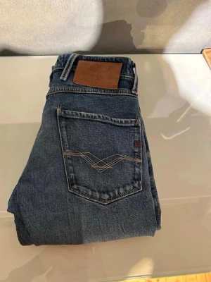 Blå jeans från Wrangler - Säljer ett par klassiska blå jeans från Wrangler med snygga kontrastsömmar och läderpatch bak i midjan. Jeansen har en rak passform och är tillverkade i slitstark denim. Perfekta för en avslappnad och cool stil.