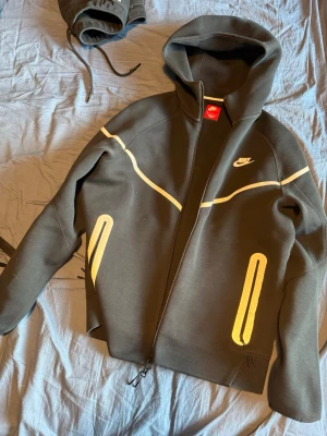Nike Tech Fleece reflective - Nike Tech Fleece set med hoodie och byxor i svart med vita reflektiva detaljer och dragkedjor. Gammal modell som ej säljs längre och mycket sparsamt använd, självklart äkta , vid frågor är det bara skicka iväg ett pm. Över delen är i storlek M men byxorna i L.