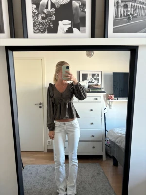 Mörkgrön blus med volang och knappar - Säljer en mörkgrön blus med v-ringning, volangdetaljer och knappar framtill. Blusen har långa ärmar och en loose passning som ger en avslappnad och trendig look. Perfekt för dig som gillar romantiska detaljer och en cool stil.