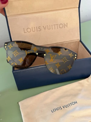 Louis Vuitton solglasögon med monogram - Original Louis Vuitton sunglasses 🖤  Model: Z1487W  Beautiful and stylish Louis Vuitton sunglasses in excellent condition.   100% authentic. No scratches on the lenses or frame.  The sunglasses were purchased a long time ago but were barely used and worn very rarely.  Comes with: • Original Louis Vuitton case   • Original dust bag  Unfortunately, the receipt and outer box are no longer available due to the age of the purchase.  Elegant monogram design and very comfortable to wear. Price: 3200sek