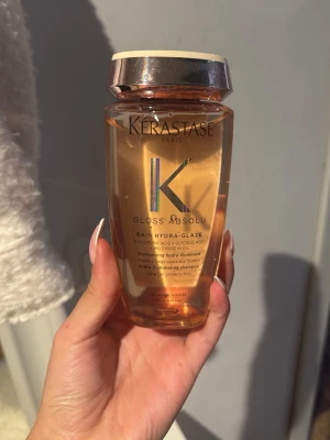 Kérastase Gloss Absolu shampoo - Kérastase Gloss Absolu Bain Hydra-Glaze är ett lyxigt schampo med hyaluronsyra och glykolsyra. Flaskan är transparent med roséguldigt lock och innehåller en glansgivande formula som motverkar friss och ger håret lyster.