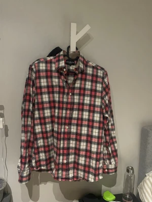 Rutig skjorta från Jean Paul  - Klassisk långärmad skjorta från Jean Paul i rött, vitt och svart rutigt mönster. Skjortan har knappar framtill och vid ärmsluten samt en mjuk bomullskänsla. Perfekt för en avslappnad men ändå stilsäker look.