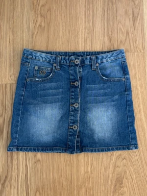 Jeanskjol - Super fin blå jeans kjol med fina knappar i fram. Storlek S. Midjemått rakt över: 36 cm Längd: 36 cm