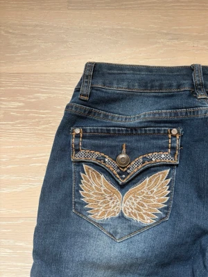 Mörkblå bottcut jeans  - Mörkblå lågmidjade bootcut jeans med strass och inbroderingar. Strl 36/regular 