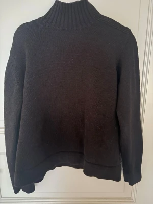 Mörkbrun stickad polotröja - Säljer en mörkbrun stickad polotröja med ribbad hög krage och långa ärmar. Tröjan har en enkel och klassisk design med ribbstickade muddar vid ärmslut och nederkant. Perfekt för dig som gillar en stilren look och vill hålla dig varm. Den har även en dragkedja vid kragen så att man kan öppna upp den upptill för en mer avslappnad look, tröja är från polarn o pyret💞