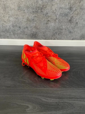 Adidas Predator - Säljer ett par grymma fotbollsskor från Adidas i starkt röd färg med neongröna dobbar, då de aldrig kommer till användning. Använda ett fåtal gånger, i väldigt bra skick. Storlek 43 och 1/3.🤩