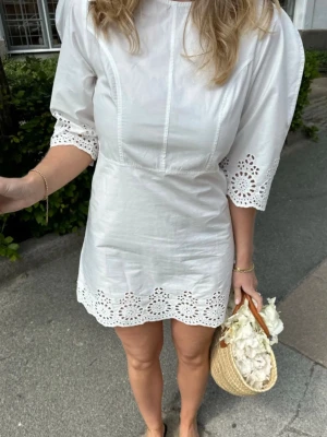 BYIC vit klänning studentklänning i stl S/M helt ny - Closefitting white dress with puffy embroidery sleeves and embroidery details in the bottom. Close it the an invisible zipper on the back.  We recommend to wear neutral colors underneath.  Längd - ca 85 cm Skulle även passa S