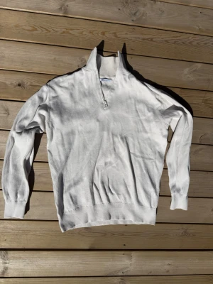 Vit halvzip tröja med hög krage - Snygg vit tröja med halv dragkedja och hög krage. Långärmad modell med ribbade muddar vid ärmslut och nederkant. Perfekt för en clean och stilren look. Materialet känns mjukt och bekvämt, passar till många outfits.