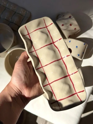 Ägghållare i keramik  - Ägghållare i keramik rutig – handgjord  Rymmer 10 ägg.  Handgjord ägghållare i keramik. Perfekt för frukostbordet eller som en fin detalj i köket.  Varje ägghållare är tillverkad för hand, vilket innebär att små variationer och naturliga ojämnheter kan förekomma – det är en del av hantverket och gör varje exemplar helt unikt.  Rekommenderas att handdiskas. Men tål diskmaskin och micro.  Handmade – fruitnclay  