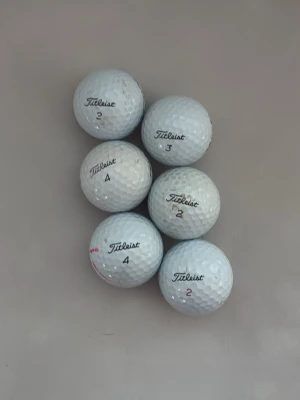 Titleist PRO v1 golfbollar, 6-pack - Säljer ett set med sex vita golfbollar från Titleist. Bollarna har klassisk rund form och är märkta med siffrorna 2, 3 och 4. Perfekt för dig som vill fylla på golfutrustningen med kvalitetsbollar.