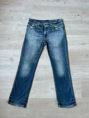 Blåa Nudie Slim Jim Jeans med Fades W32 L32 - Fina Nudie Jeans i blå färg. Jeansen är i mycket bra skick och sparsamt använda.  Äkta som allt annat jag säljer! ✅  Storlek: W32 L32 Skick: Mycket Bra Skick - lite sönder vid botten av byxbenen, (SE SISTA 2 BILDER) Färg: Blå Märke: Nudie Modell: Jeans    Hör gärna av dig vid frågor så svarar jag så fort jag kan! 😁  (SKU - 94)