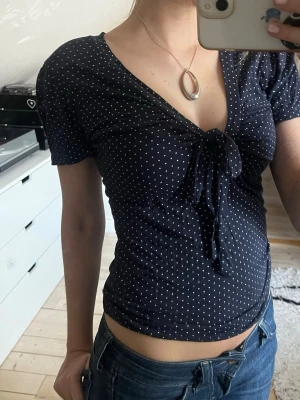 Mörkblå prickig topp med knyt framtill - Så snygg prickig topp med knyt framtill! Köpt second hand men sparsamt använd. Uppskattas som storlek S. 