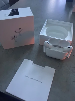 Apple AirPods Pro med laddningsetui - Säljer ett par vita Apple AirPods Pro med trådlöst laddningsetui. Hörlurarna har en stilren och kompakt design i plast och levereras med originalförpackning, laddningskabel och tillbehör. Perfekta för musik, samtal och träning. Säljer dom för har hittat mina gamla som jag va av me 