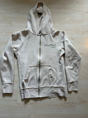 Beige Hard Rock Cafe hoodie - Beige hoodie med dragkedja från Hard Rock Cafe. Köpt på Sellpy men var för liten, den kom med ett litet hål som nu är lagat. Kolla min bio