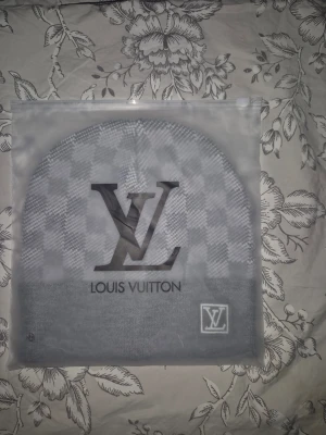 Grå Louis Vuitton mössa - Snygg grå mössa från Louis Vuitton med klassiskt rutmönster och stor LV-logga framtill. Mössan har vikt kant med en liten LV-patch på sidan. Perfekt accessoar för dig som gillar exklusiv streetstyle och vill sticka ut med ett lyxigt märke.