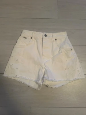 Pepe jeans vita högmidjade shorts med broderi - Säljer ett par vita högmidjade shorts från Pepe jeans med broderade detaljer och rå kant nertill. Perfekta för sommaren och ger en fräsch look. Shortsen är helt oanvända men ingen prislapp kvar tyvärr. 💕