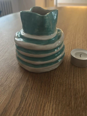 Randig keramikvas i grön och vitt - Unik handgjord keramikvas med vågig öppning och randigt mönster i grön  och vitt. Vasen har en organisk form och är tillverkad i glaserad keramik. Perfekt som dekoration eller för små blommor. 