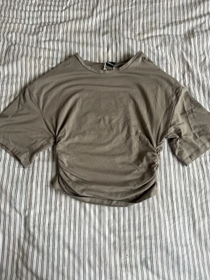   topp från Gina Tricot - Snygg croppad topp från Gina Tricot med korta ärmar och rund halsringning. Toppen har en enkel och stilren design som passar perfekt till jeans eller kjol. Mjuk och skönt i materialet, perfekt för en avslappnad look.