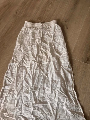 Vit långkjol med snörning - Luftig vit långkjol med resår i midjan och snörning framtill. Kjolen är tillverkad i ett tunt och mjukt bomullstyg, perfekt för varma dagar. Enkel och stilren design som passar till många olika looks.