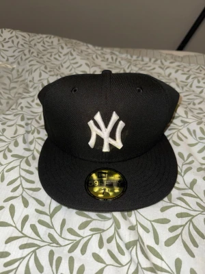 Svart New Era Yankees keps - Säljer en svart New Era 59FIFTY keps med klassiskt New York Yankees broderat vitt logotyp framtill. Kepsen är helt ny och har storlek 7 1/4 (57,7cm)