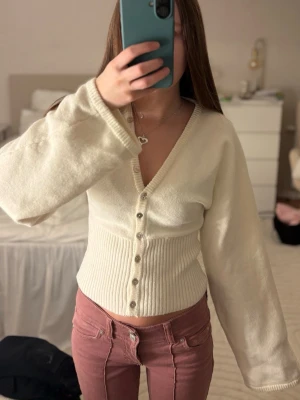 Krämvit ribbad kofta med knappar - Snygg och trendig krämvit kofta med djup v-ringning och snygga knappar. Använd nån enstaka gång, så jättebra skick! 🩷 
