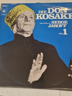 Columbia Die Don Kosaken Serge Jaroff Vol. 1 vinylskiva - Columbia Die Don Kosaken under ledning av Serge Jaroff Vol. 1 vinylskiva.  LP med körmusik framförd av Donkosackkören under ledning av Serge Jaroff. Omslaget är blått på framsidan med dirigentporträtt och vit baksida med låtlista och bilder på andra utgåvor. Standard 12" LP-format, stereo. Passar för uppspelning på skivspelare som klarar vinyl i 33 1/3 rpm.