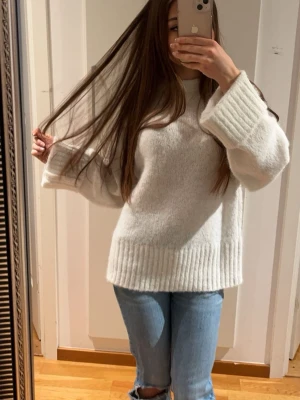 Vit stickad tröja - Mysig vit stickad tröja med lite oversized passform och breda ribbade muddar vid ärmslut och nederkant. Tröjan är bara använd 1 gång. På bilden har jag vikt ärmarna eftersom de är för långa för mig.