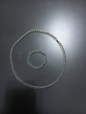 halsband och armband i silverfärgad metall - Säljer ett stilrent halsband och armband i silverfärgad metall med grova länkar och klassiskt karbinlås. Perfekt för dig som gillar en enkel men edgy look. Passar både till streetwear och mer minimalistiska outfits. Jag behöver inte det för att jag beställde en bättre halsband och armband.