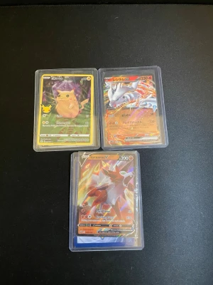 Pokémonkort samling i plastfickor - Säljer en samling Pokémonkort med motiv av Pikachu, Reshiram, Lycanroc, Keldeo, Lugia och Ho-Oh. Korten har färgstarka illustrationer och ligger i genomskinliga plastfickor. Perfekt för dig som gillar att samla eller spela Pokémon TCG.