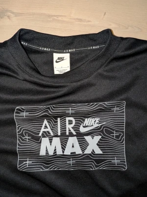 Nike Air Max svart sweatshirt - Svart sweatshirt från Nike med stort vitt Air Max-tryck på bröstet och grafiskt mönster runt loggan. Rund halsringning och långa ärmar. Perfekt för en sportig och avslappnad stil.